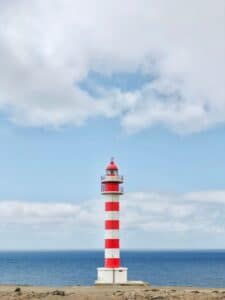 Red and white lighthouse against blue sky