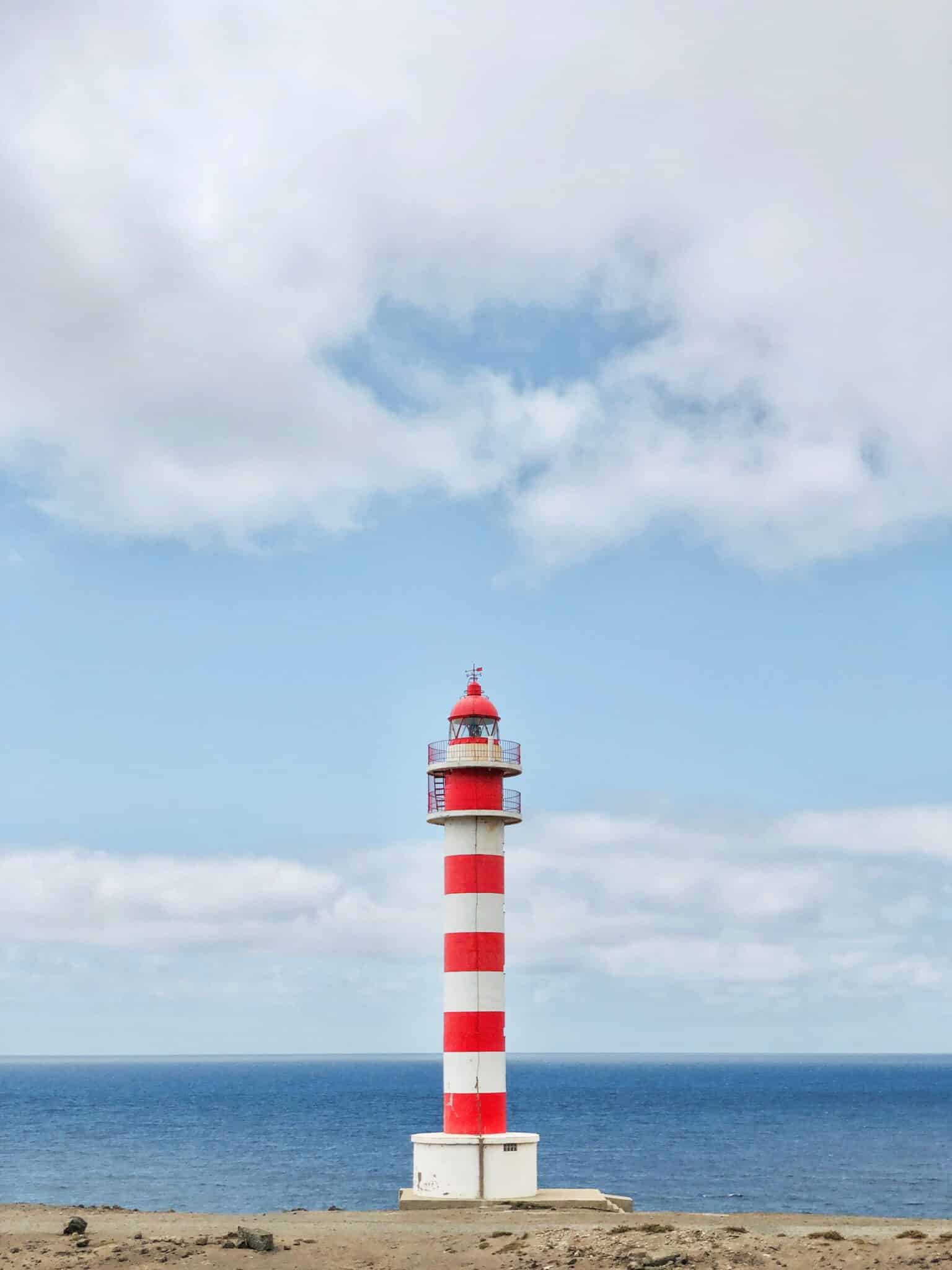Red and white lighthouse against blue sky