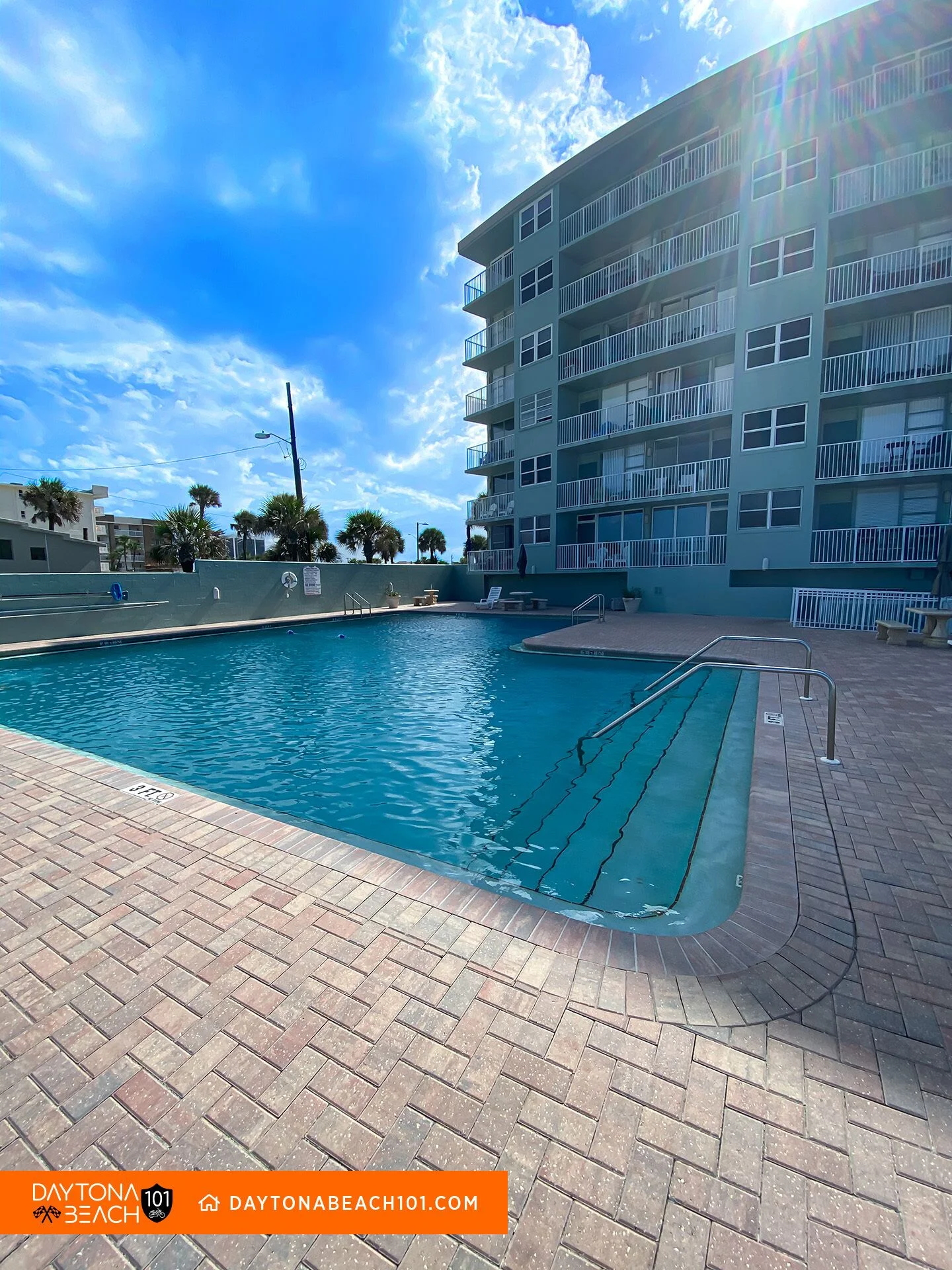Oceanfront vacation rental pool with lounge chairs and palm trees in Daytona Beach